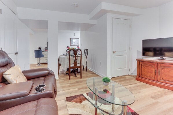 A modern living room with a leather sofa, glass coffee table, and wooden dining table.