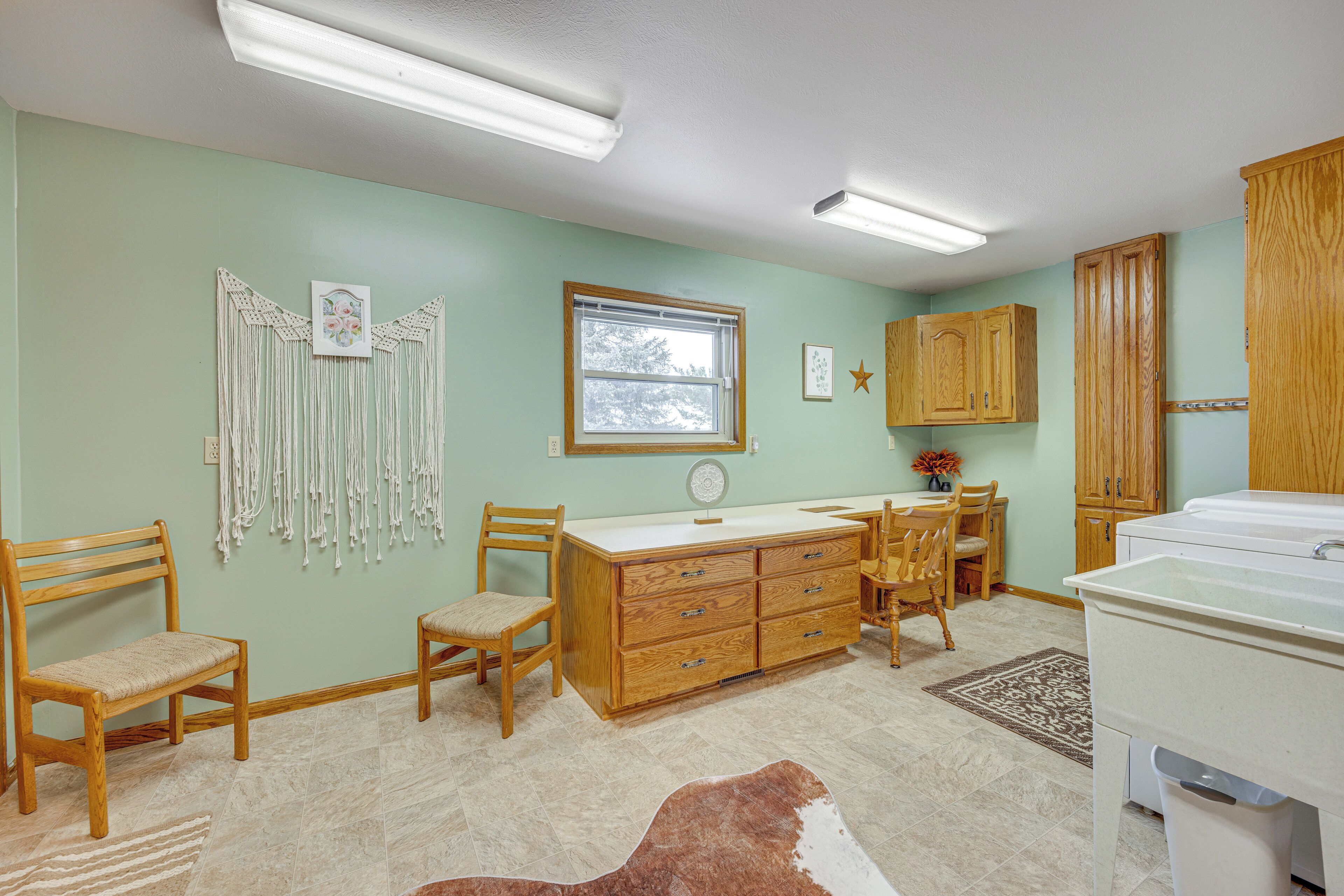 A room with a wooden desk, two chairs, a dresser, and a washing machine.
