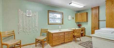 A room with a wooden desk, two chairs, a dresser, and a washing machine.