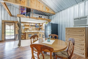 Une cuisine rustique avec des meubles de rangement en bois, une table Ă manger, des chaises et une grande fenĂȘtre.