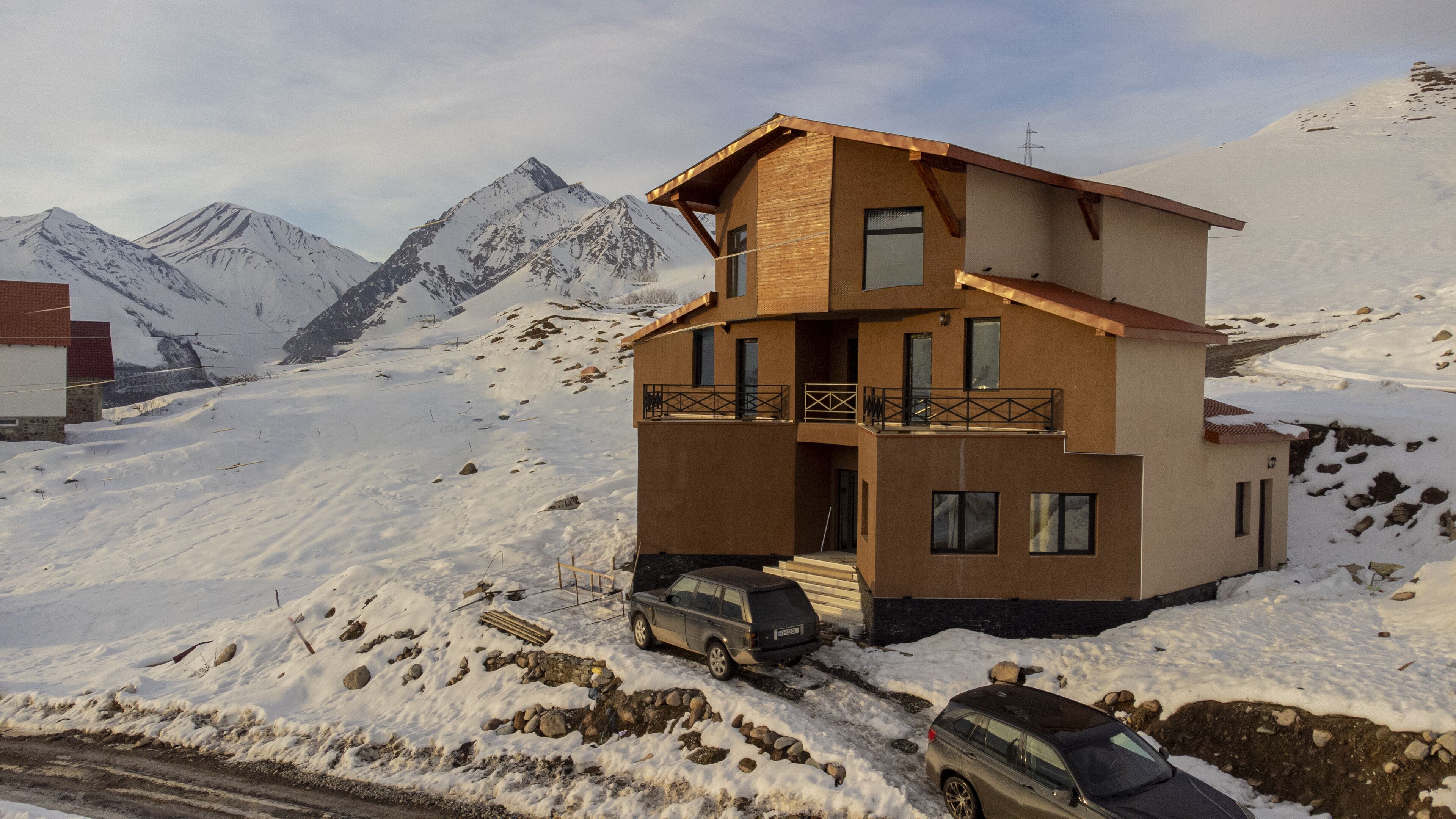 Un chalet à deux étages doté d’un balcon, entouré de montagnes enneigées.