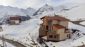 Eine zweistöckige Berglodge mit Balkon, umgeben von schneebedeckten Bergen.