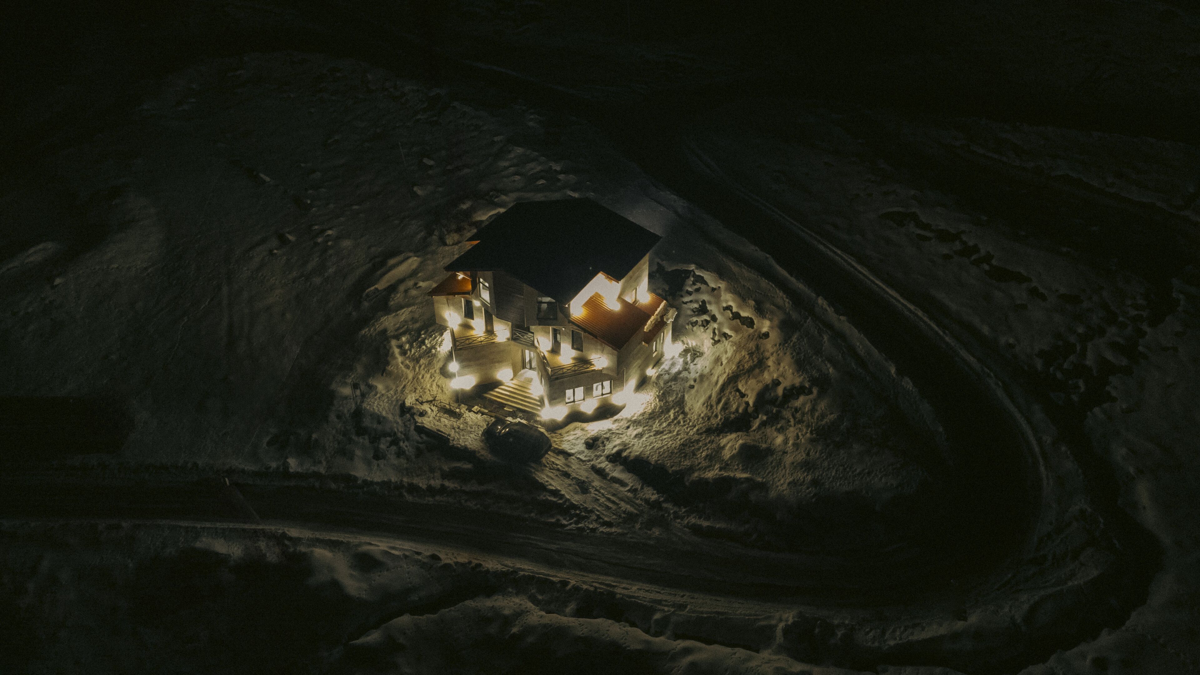 A cave with a small illuminated structure inside, possibly a cave dwelling or a tourist attraction.