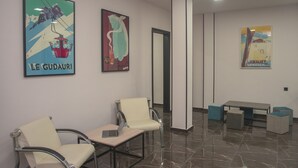 Eine Wartezone mit zwei Sesseln, einem Tisch und drei Bildern an der Wand.