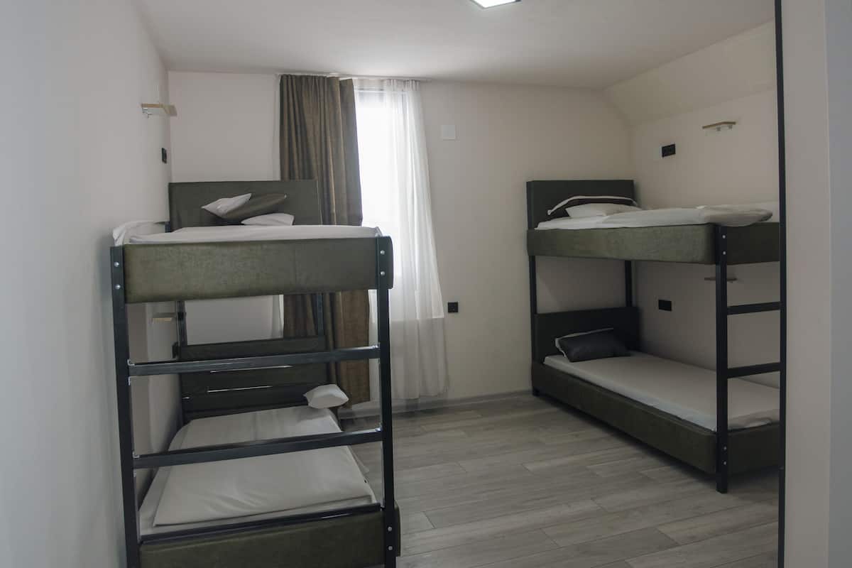 Una habitación con literas, una ventana con cortinas y una lámpara en el techo.