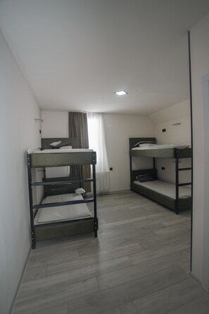 A room with bunk beds, a window with curtains, and a ceiling light.