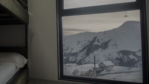 Ein Zimmer mit großem Fenster und Blick auf eine verschneite Berglandschaft.