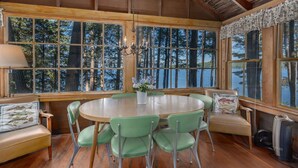 A wooden cabin with a round dining table, green chairs, and a bench. - Lake Winnipesauke compound sleeps 22 in 13 bedrooms stunning sunset views (Alton Bay)