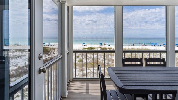 A covered outdoor area with a view of the beach, a table, and chairs.