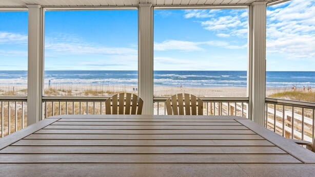 A covered outdoor seating area with a view of the beach and ocean.