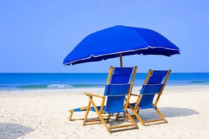 Relax in comfort under a spacious umbrella, surrounded by the soothing sounds of the ocean.