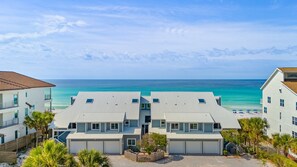 Enjoy stunning ocean views from this beachfront property with modern, two-story buildings surrounded by lush greenery and palm trees.