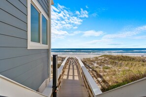 Ein Holzweg, der zu einem Strand führt, mit freiem Blick auf das Meer.
