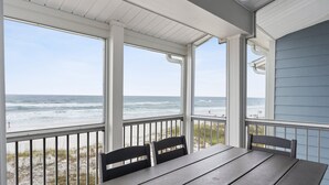 A covered outdoor seating area with a view of the beach and ocean.