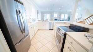 A modern kitchen with stainless steel appliances, white cabinetry, and a tiled floor. - Dog-Friendly, Pool & Tennis Court, Hot Tub in Sunset Beach! (St. George Island)