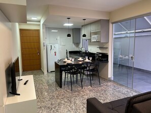 A compact kitchen with a dining area, a refrigerator, a microwave, and a stove. - Lockings Savassi 12 (Belo Horizonte)