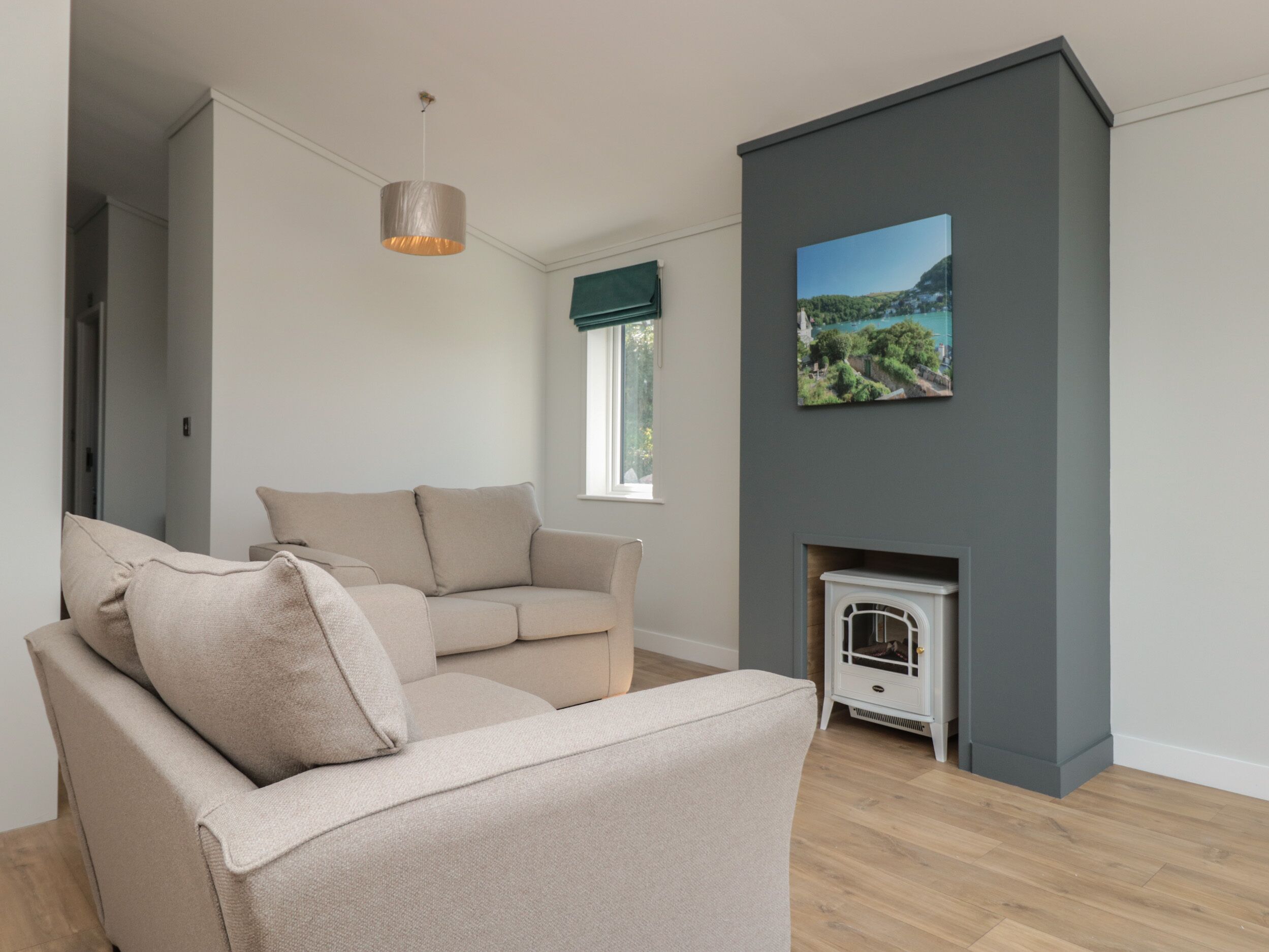 A living room with a beige sofa, a white fireplace, and a painting of a landscape.