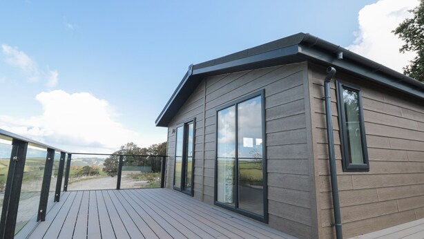 A modern house with a deck, large windows, and a view of the countryside. - Primrose Lodge (Dartmouth)