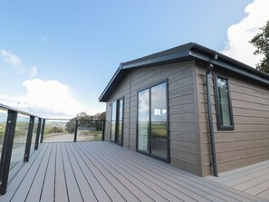 Une maison moderne dotée d’une terrasse, de grandes fenêtres et offrant une vue sur la campagne.