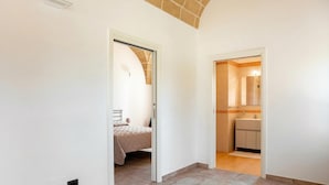 A hallway leading to a bedroom and a bathroom, with a tiled floor and white walls.