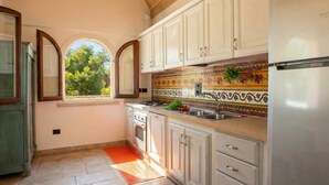 A kitchen with white cabinets, a stainless steel refrigerator, and a colorful backsplash.