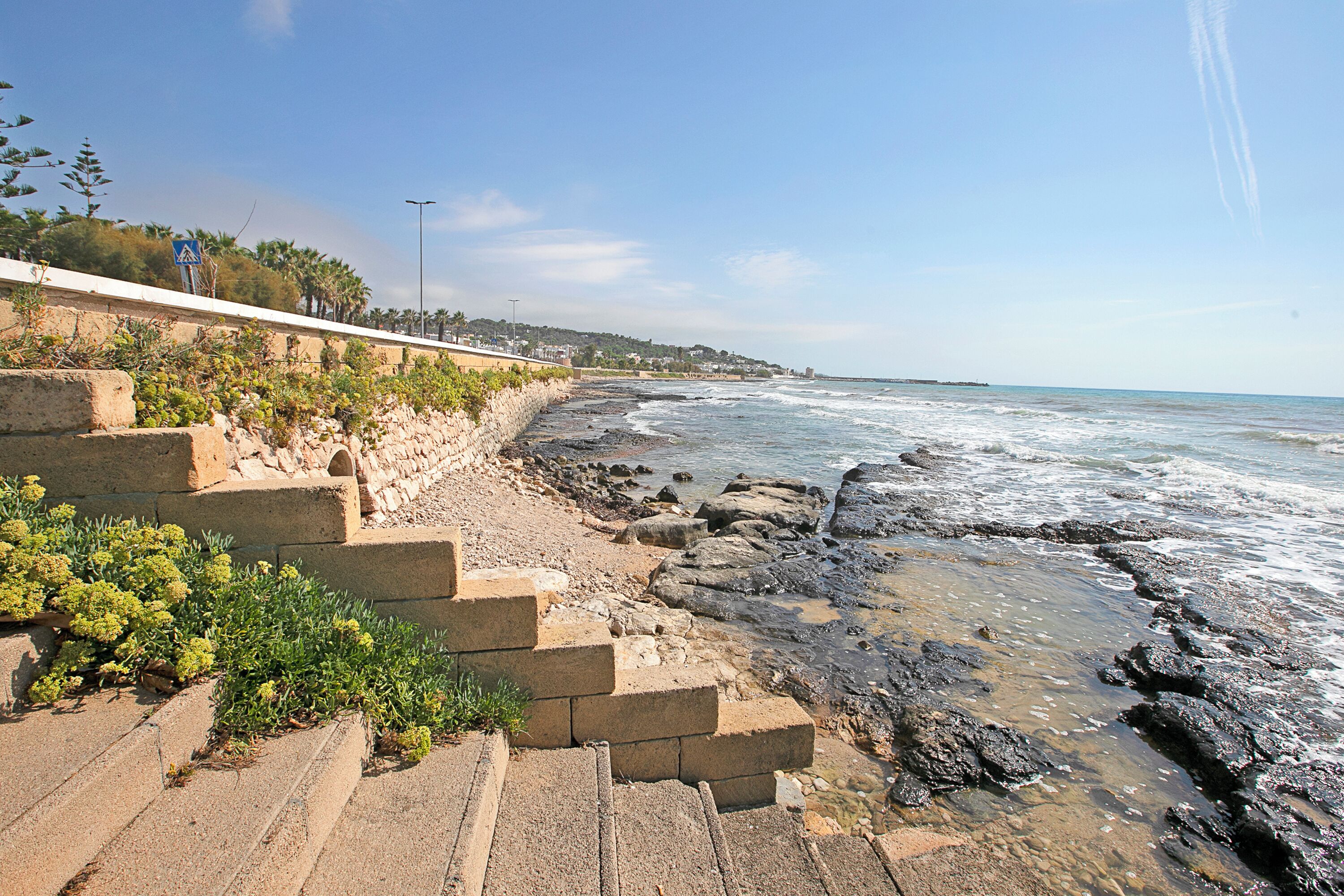 A coastal walkway with stone steps leading to the beach, overlooking the ocean.