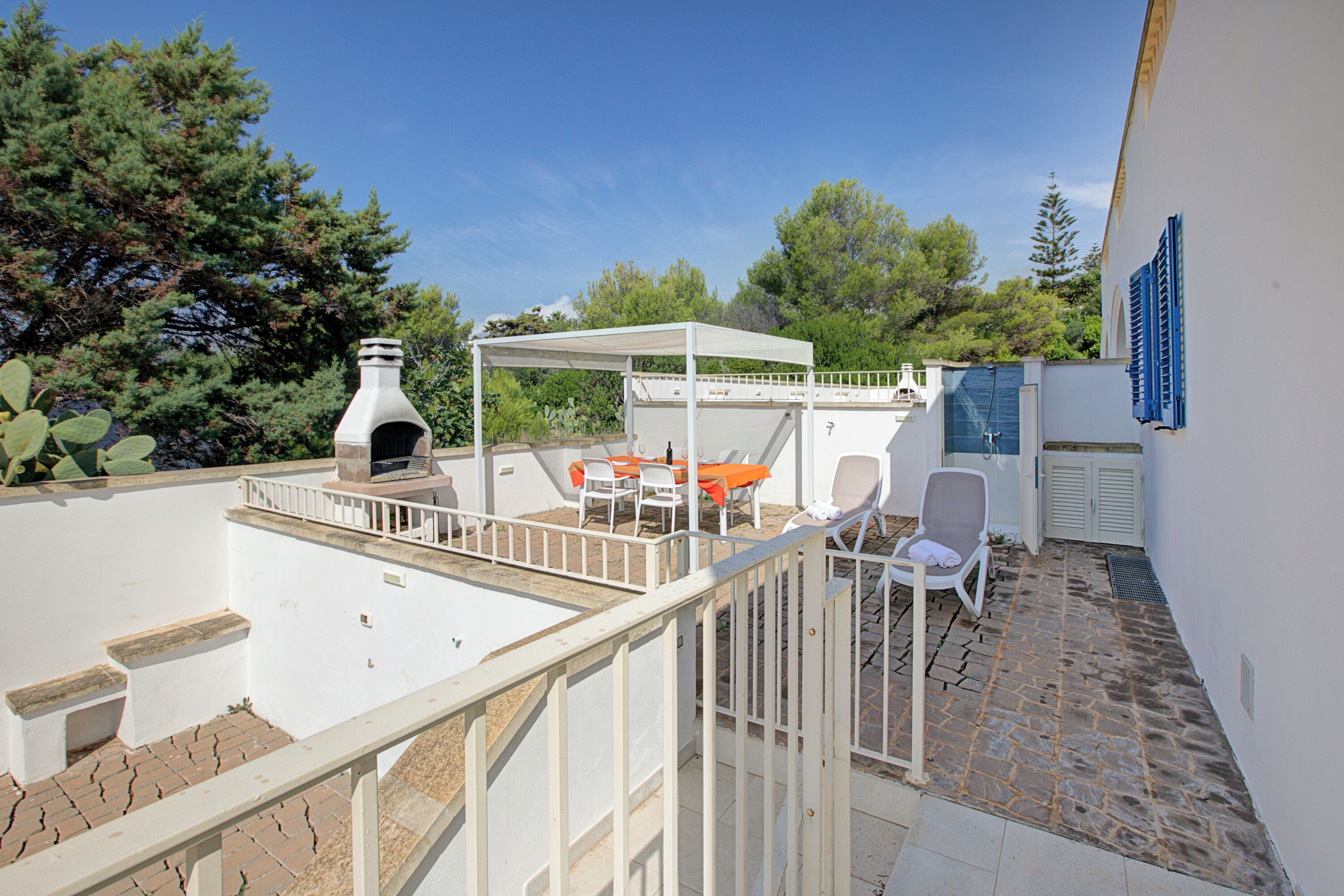 Una terraza en la azotea con una parrilla, muebles de exterior y una piscina.