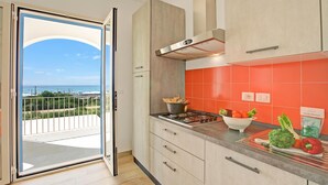Cocina moderna con vistas al exterior, una estufa y una variedad de productos frescos sobre la encimera.