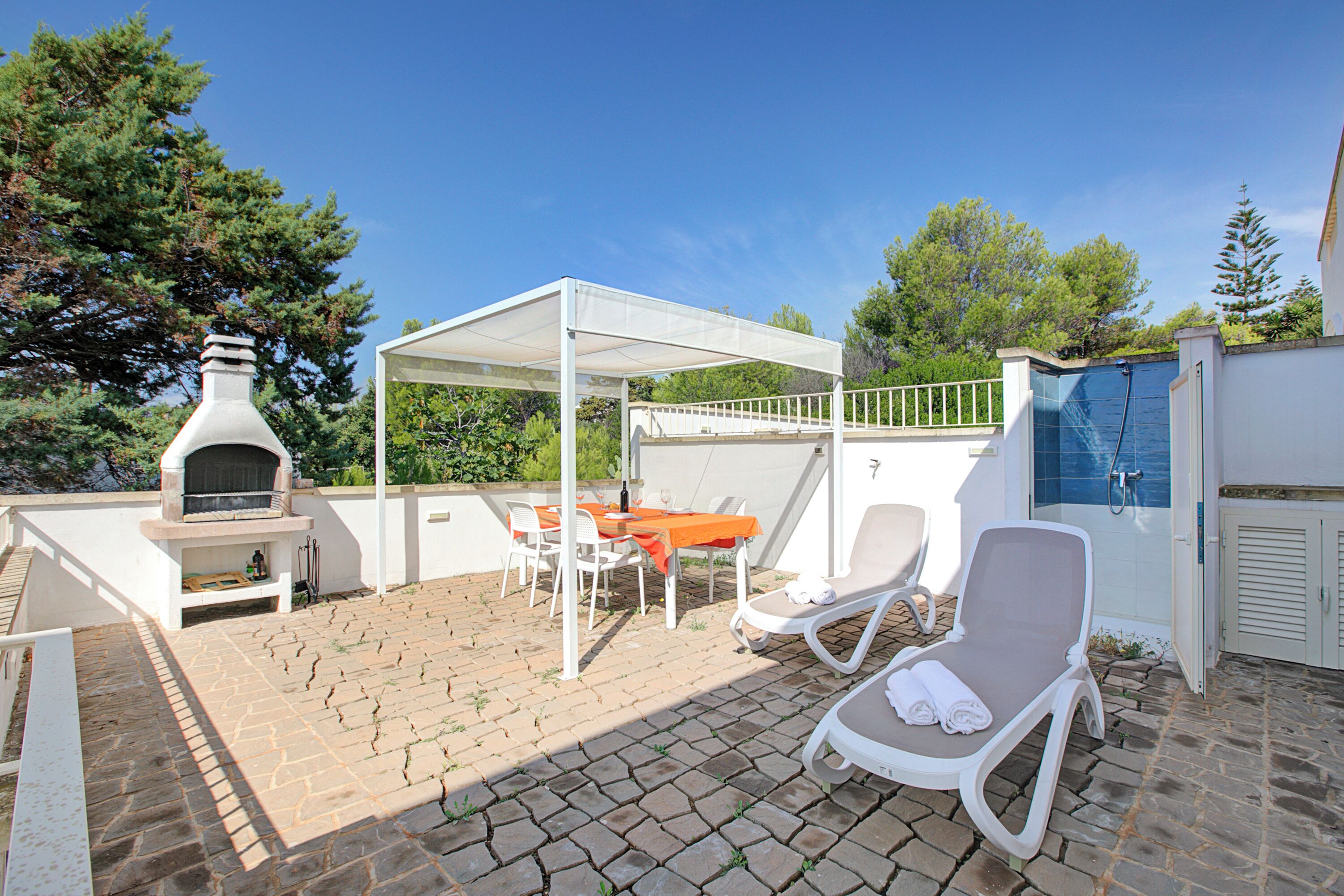 A patio with a barbecue, outdoor seating, and a covered area.