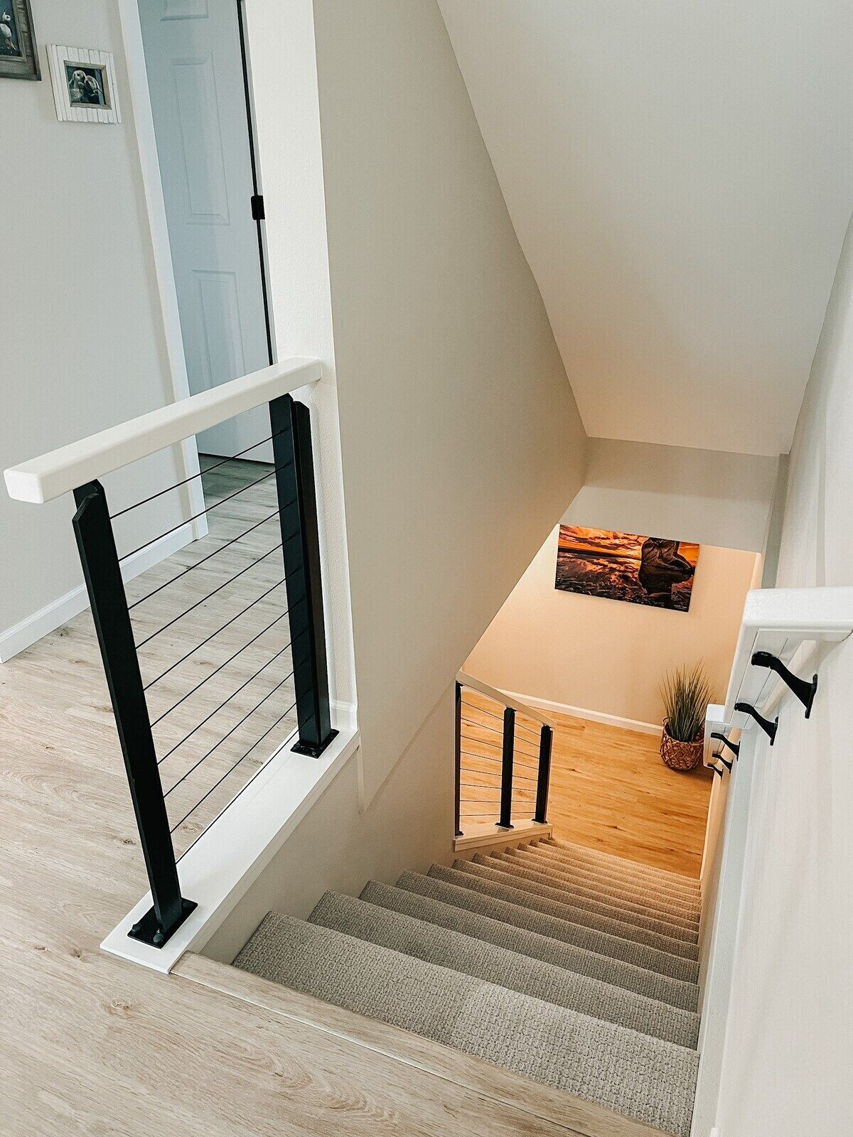 A modern staircase with a wooden finish, a white railing, and a small table with a plant.