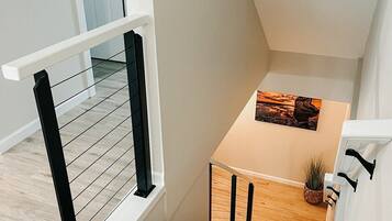 A modern staircase with a wooden finish, a white railing, and a small table with a plant.