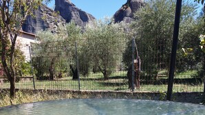 A clear pool with a view of rocky mountains and trees in the background. - Kastraki House with a view (Kalabaka)