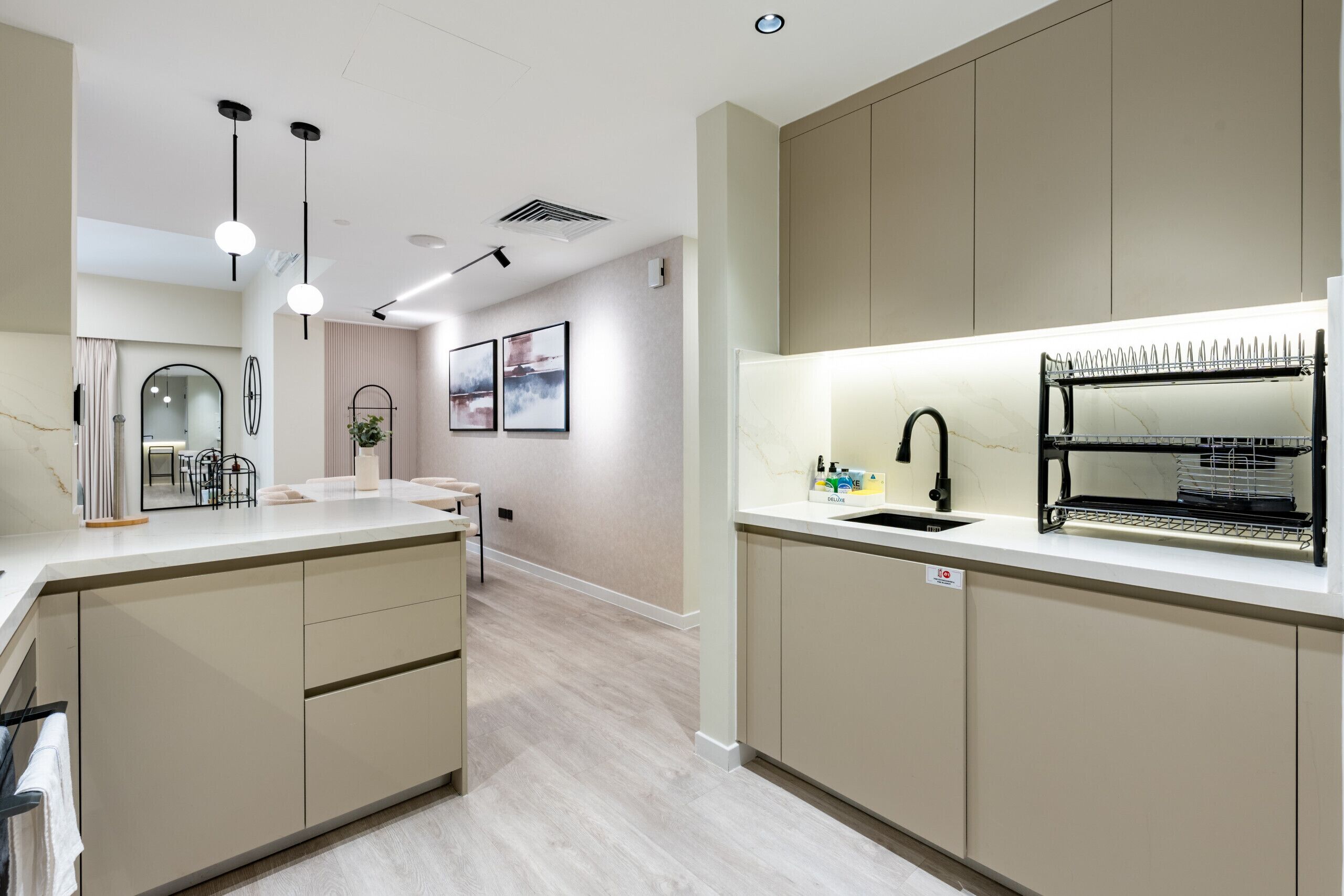 Une cuisine moderne dotée d’un îlot central, de luminaires suspendus et d’un lave-vaisselle encastré.