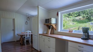 A kitchen with wooden cabinets, a dining table, and a window with a view of greenery.