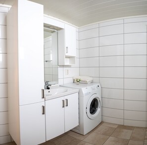 A modern bathroom with white cabinetry, a sink, a mirror, and a front-loading washing machine. - Mountain View - 30min From OSL (Innlandet)