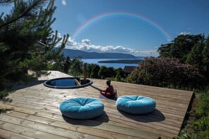 A wooden deck with two blue bean bags, a hot tub, and a view of a lake with mountains in the background. - Mountain View - 30min From OSL (Innlandet)