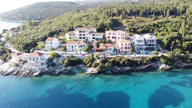 An aerial view of a coastal residential area with buildings surrounded by clear blue waters and dense greenery. - Tassos Cottage Fiskardo Kefalonia (Kefalonia)