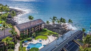 A resort with a swimming pool, solar panels, and a view of the ocean. - Kona Makai 1-103 Nearly Oceanfront, Ground Floor, No Stairs, Special Location (Kailua Kona)