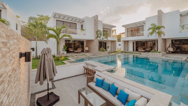 A modern outdoor pool area with a glass table, a sofa with blue cushions, and a patio umbrella. - Beach House in Monterrico Guatemala (Taxisco)