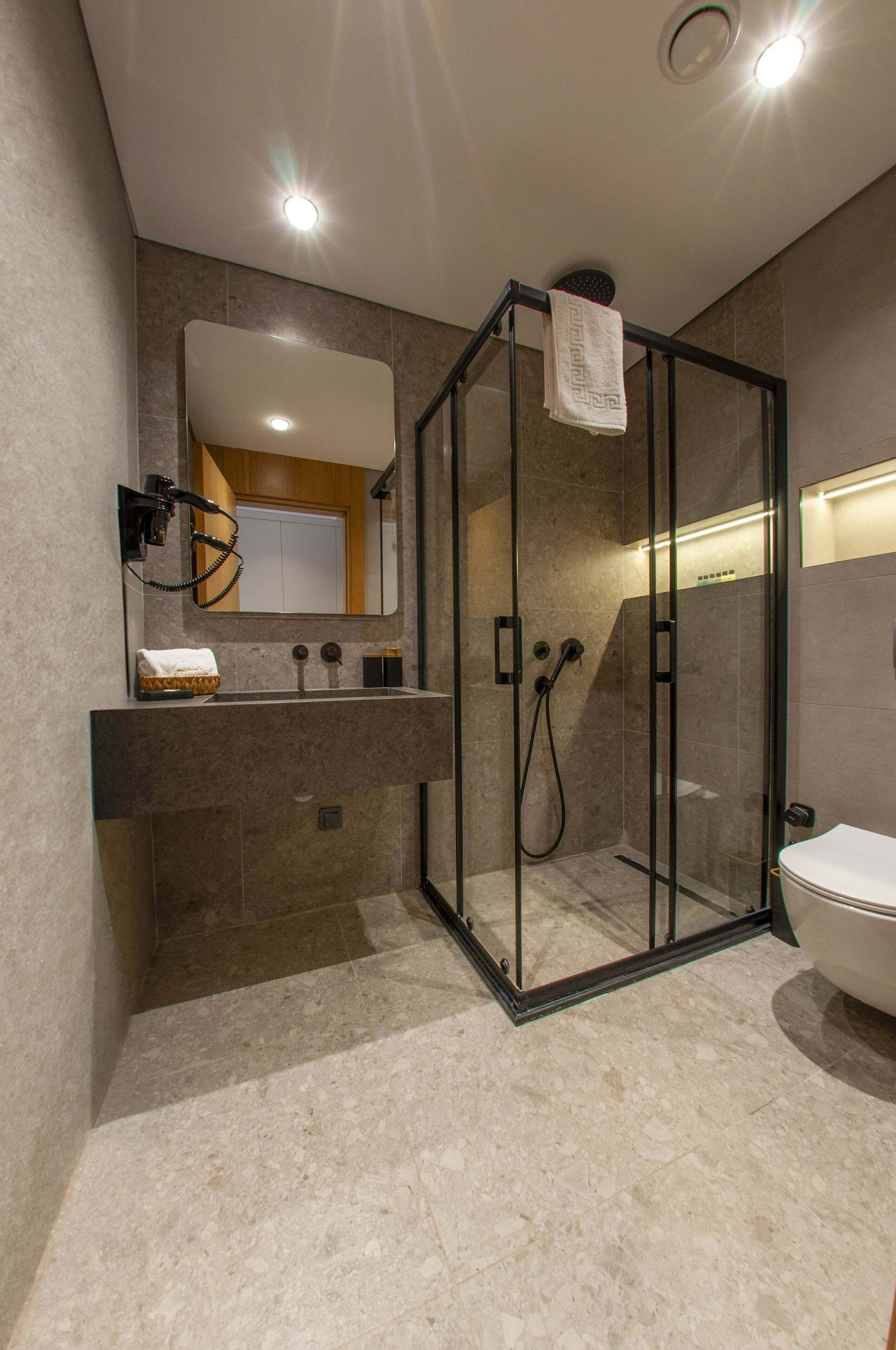 Ein modernes Badezimmer mit einer Duschkabine aus Glas, einem Waschtisch mit Spiegel und einer Toilette.