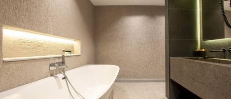 A modern bathroom with a freestanding bathtub, a vanity with a mirror, and a towel rack.