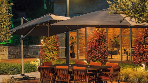A modern house with a patio area featuring outdoor furniture and a large umbrella. - Melekona House (Kartepe)