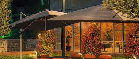 Une maison moderne dotée d’un patio aménagé avec du mobilier d’extérieur et un grand parasol.