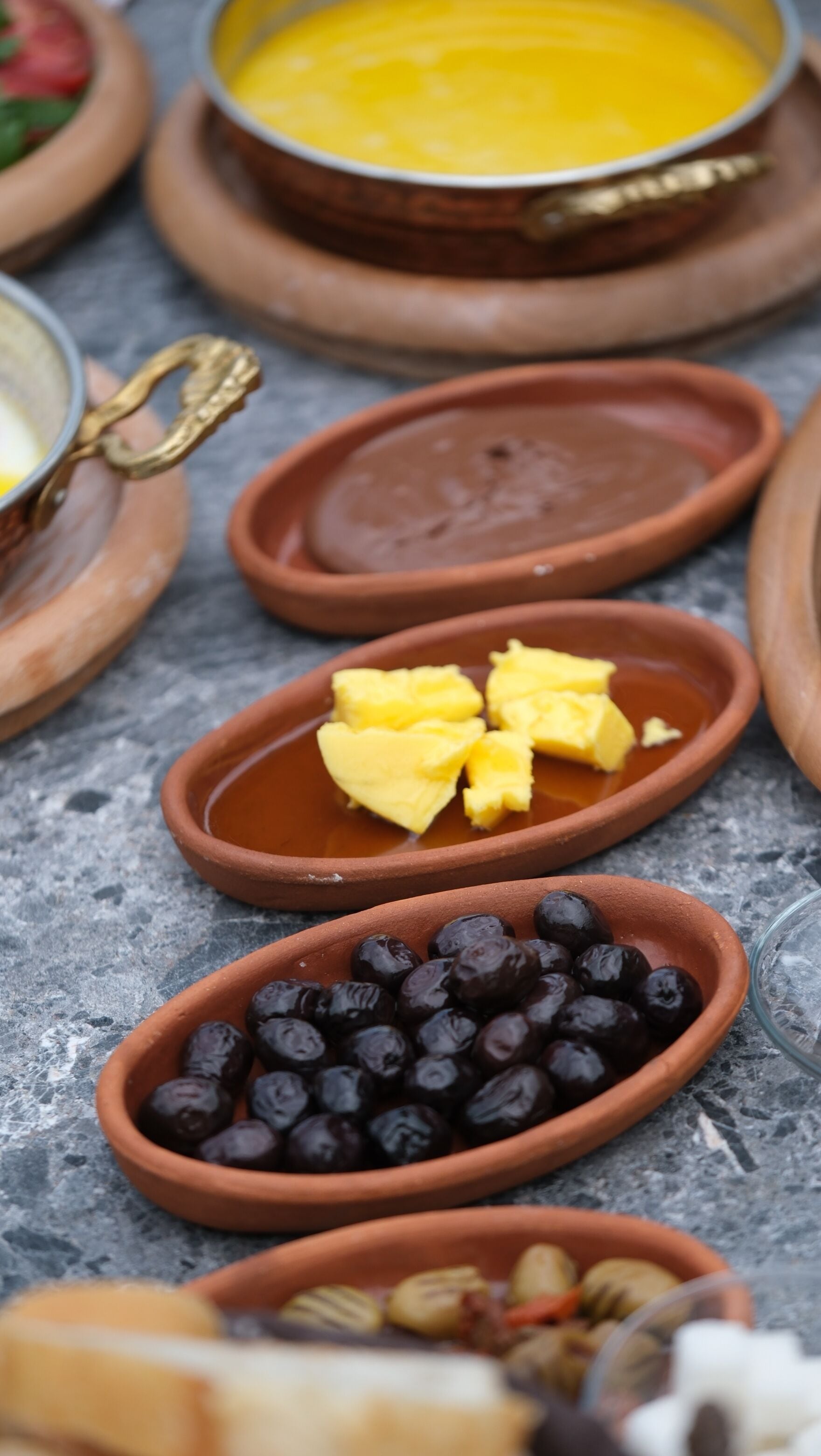 Diversos alimentos servidos en recipientes de barro sobre una superficie de mármol.