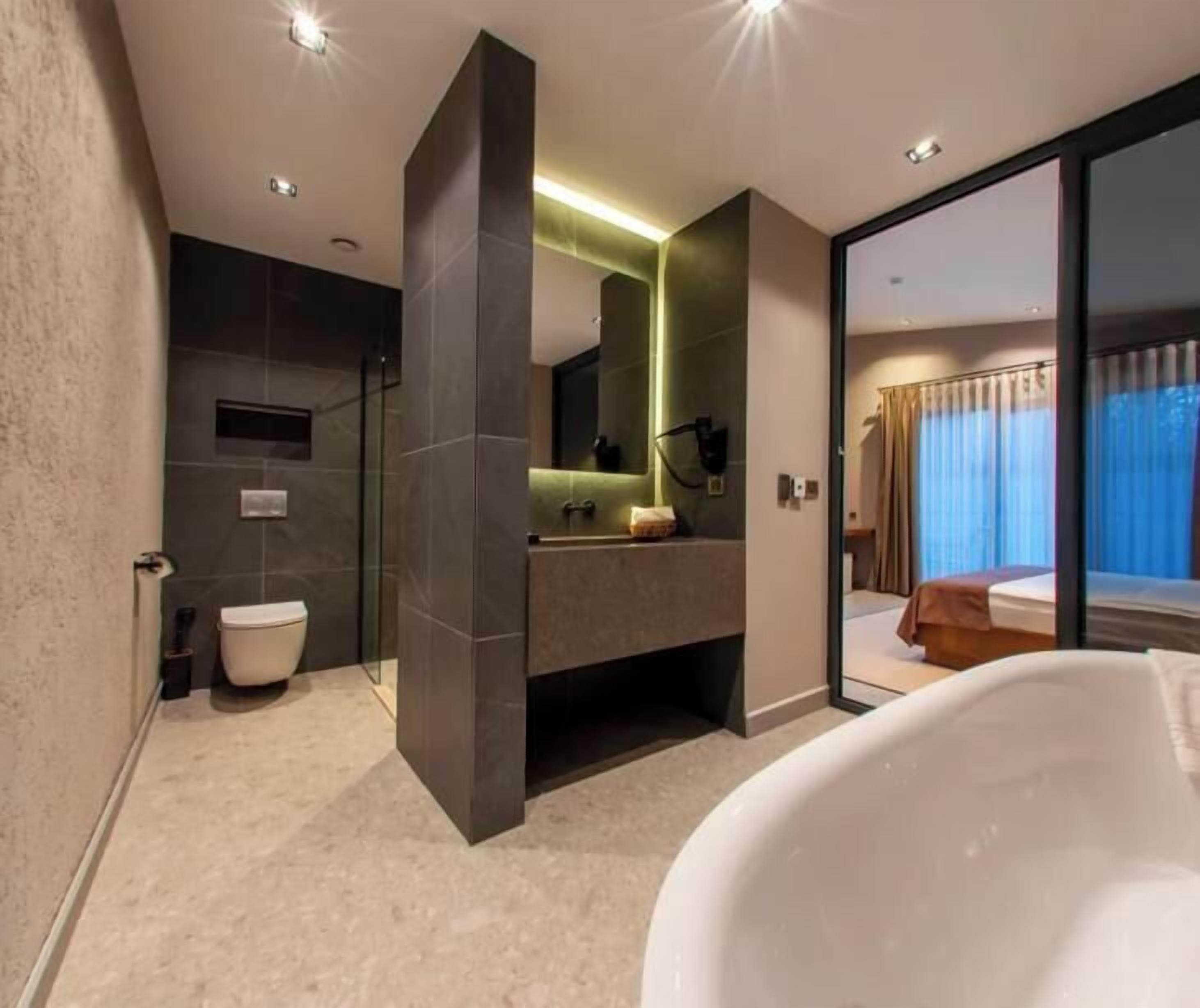 A modern bathroom with a glass shower enclosure, a standalone bathtub, and a visible toilet.