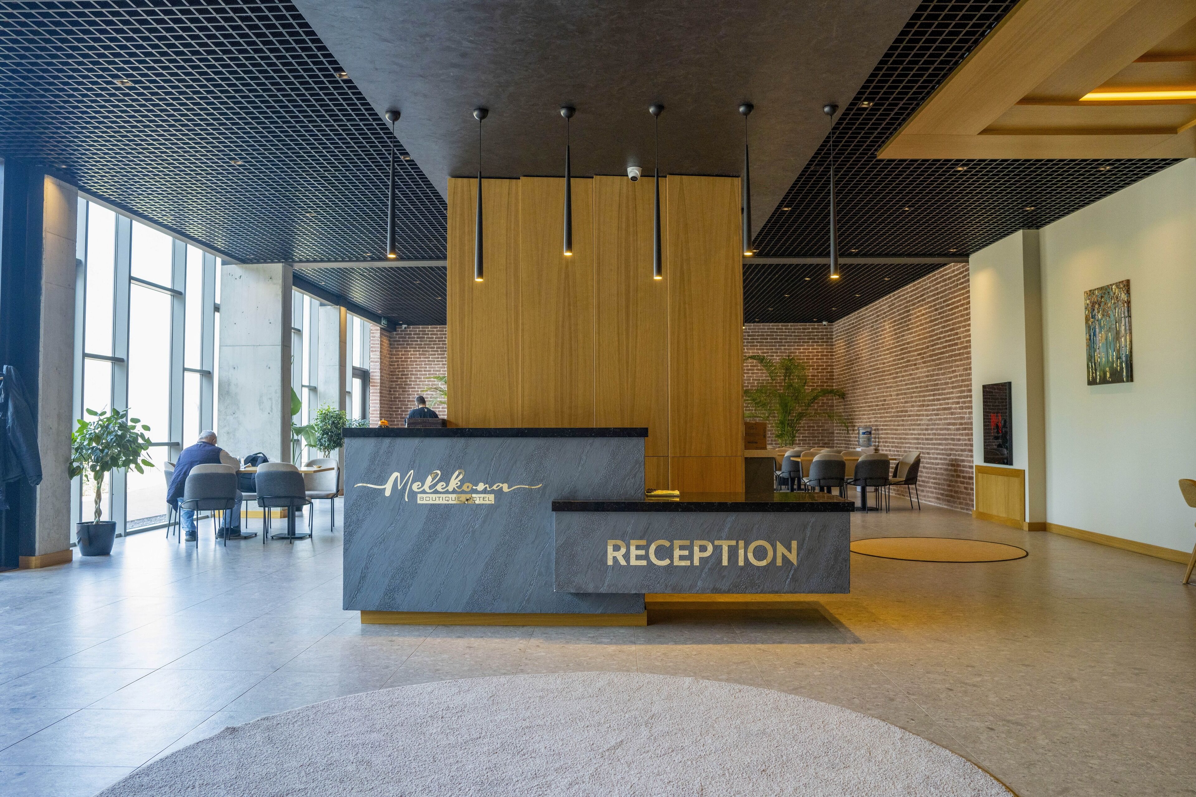Moderne reception med skrivebord, siddeområde og store vinduer, der lukker naturligt lys ind.