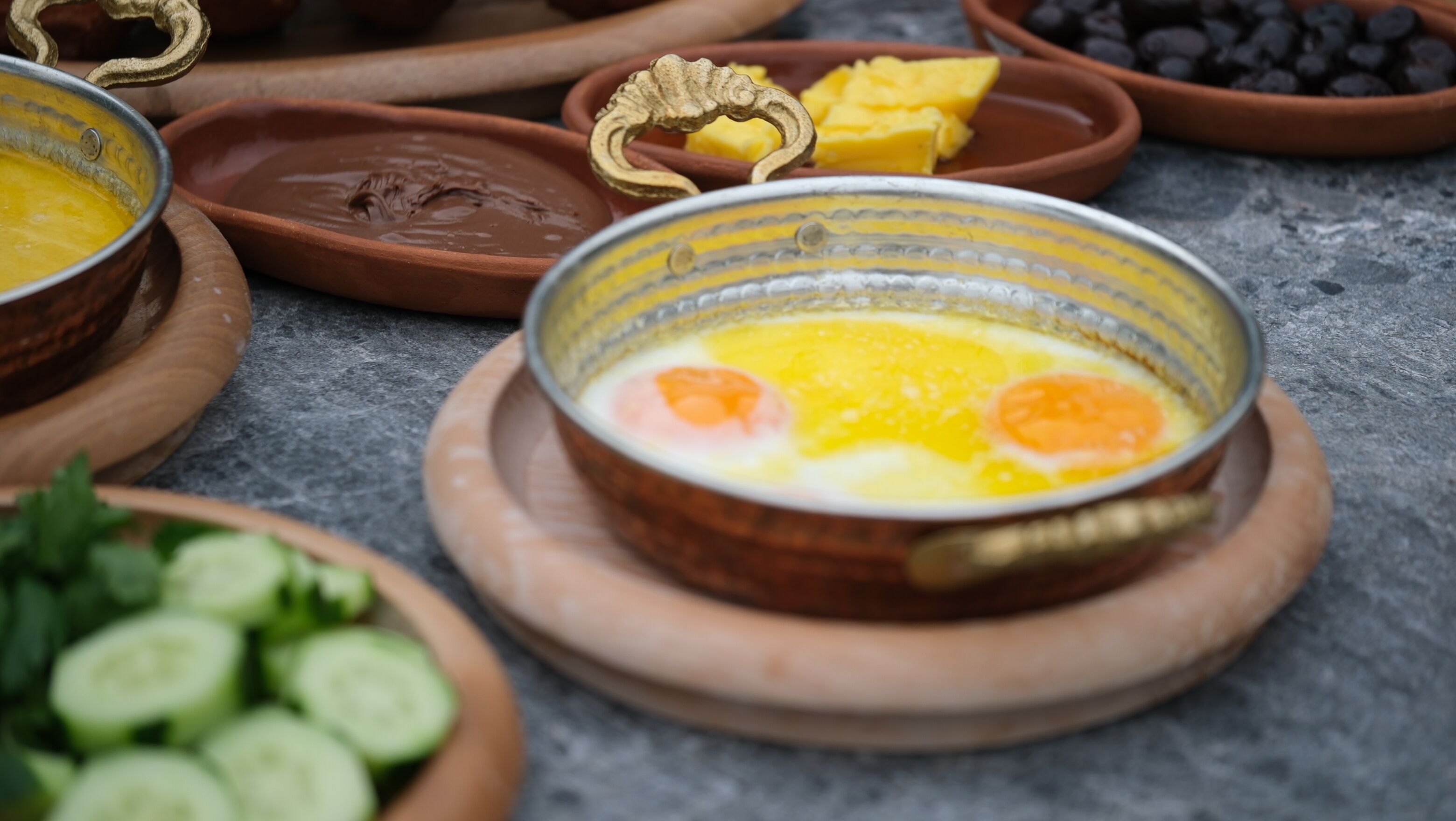 Une table mise pour le petit-déjeuner, avec un bol d’œufs et divers fruits et légumes.