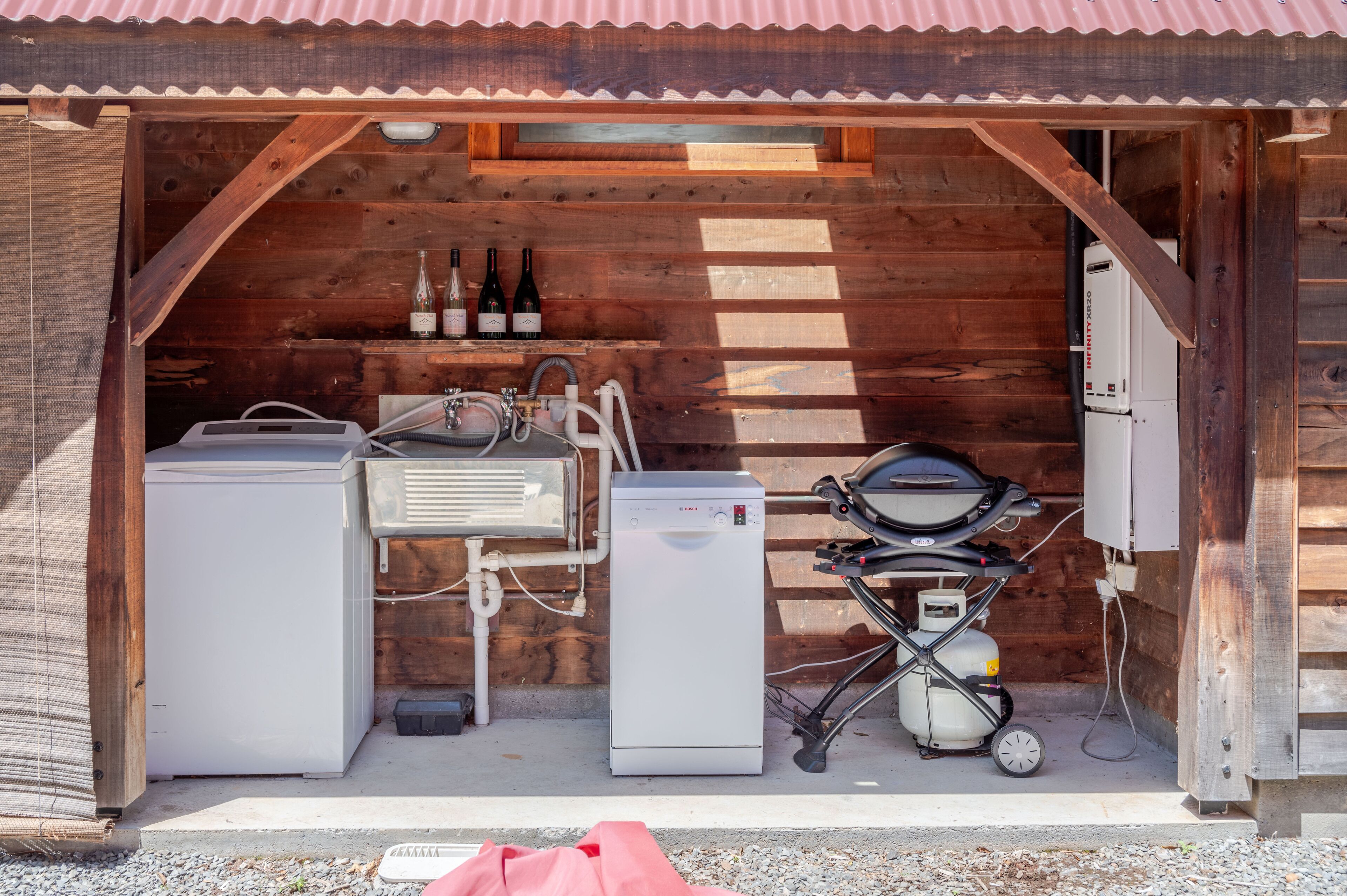 A wooden cabin with a small kitchen area, including a refrigerator, a sink, and a grill.