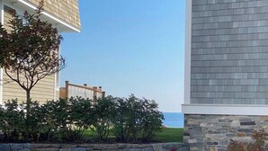 Zona residencial con un muro de piedra, una terraza de madera y vista al océano.