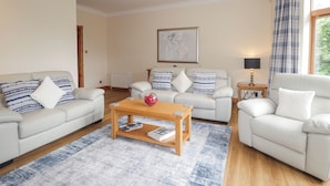 Ein modernes Wohnzimmer mit zwei weißen Sofas, einem Holztisch und einem blau gemusterten Teppich.